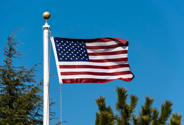 Ondeando la bandera americana contra el cielo azul, ondeando la bandera de Estados Unidos