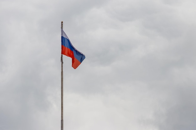 Ondeando la bandera de Rusia contra el cielo nublado sombrío