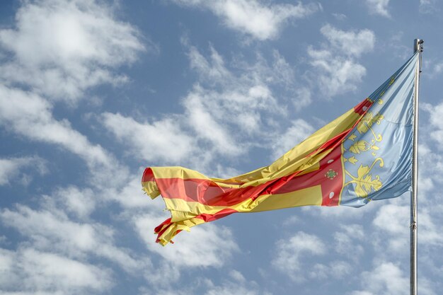 Foto ondeando la bandera de valencia españa en el cielo azul