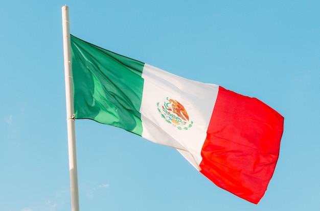 Ondeando la colorida bandera de México en el cielo azul.