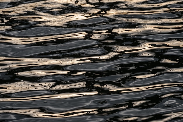 Ondulação da superfície da água do rio com reflexo e brilho dourado