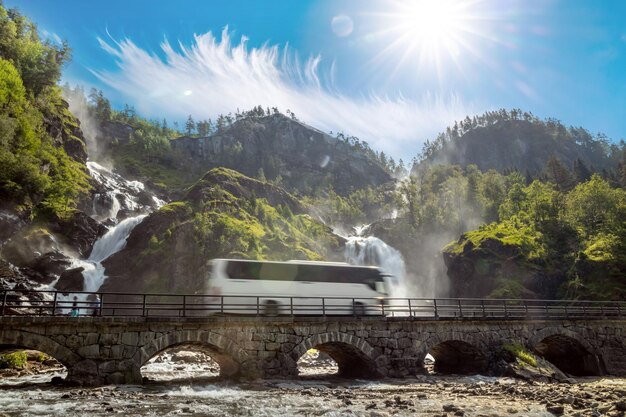 Foto Ônibus turístico viajando na estrada latefossen waterfall odda noruega latefoss é uma poderosa cachoeira gêmea