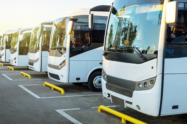 Foto Ônibus turísticos brancos no estacionamento ao nascer do sol. turismo automotivo de verão.