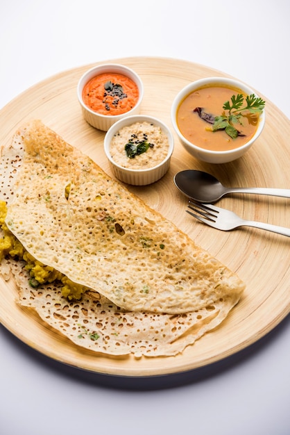 Onion rava masala dosa ist ein südindisches Instant-Frühstück, das mit Chutney und Sambar auf stimmungsvollem Hintergrund serviert wird. selektiver Fokus