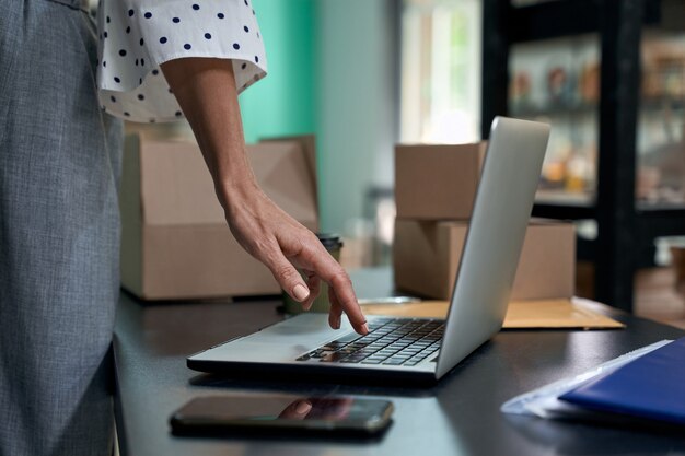 Online-Bestellungen nehmen abgeschnittene Aufnahme einer weiblichen Geschäftsinhaberin mit Laptop im Stehen