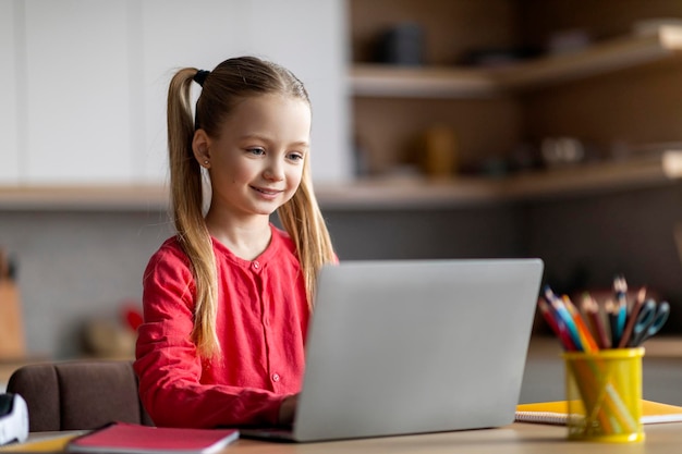Online-Bildung lächelndes süßes kleines Mädchen studiert mit Laptop zu Hause