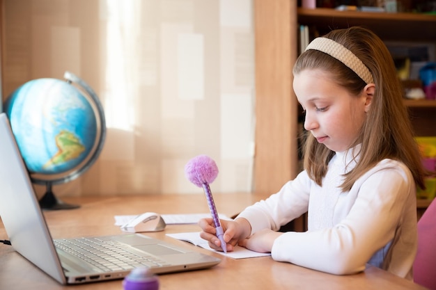 Online-Bildung von Kindern, Schulmädchen unterrichtet eine Unterrichtsstunde online über eine Laptop-Video-Chat-Anrufkonferenz mit einem Lehrer bei Homepupil unter Verwendung von Konferenzen auf Laptop mit Remote-Lehrer-Tutor