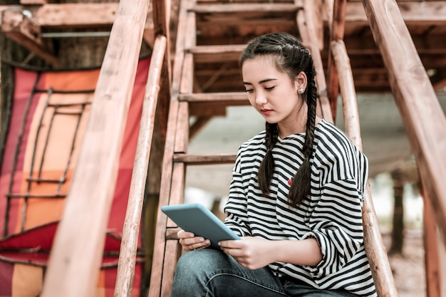 Online Chat. Schönes Mädchen, das Kopf beim Lesen der Nachricht verbeugt