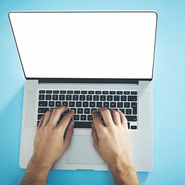 Online é onde tudo está acontecendo Foto de estúdio de um homem digitando em um laptop com uma tela em branco contra um fundo azul
