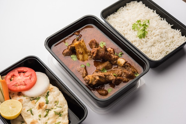 Online Food Delivery - Hammel ODER Gosht Masala ODER indisches Lamm Rogan Josh in einem Plastikbehälter zur Abholung bereit