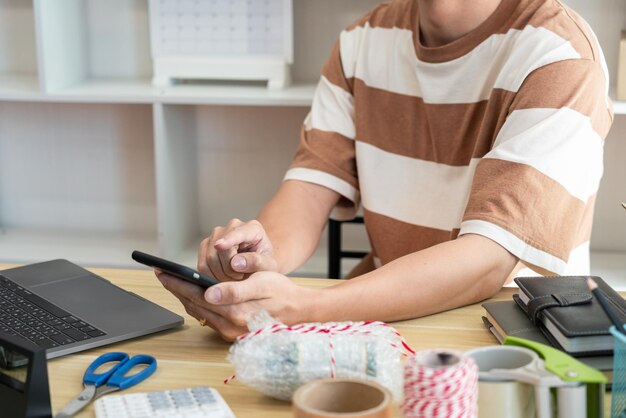 Online-Händler, der das Mobiltelefon verwendet, um die Summe der Bestellungen von Online-Kunden zu überprüfen