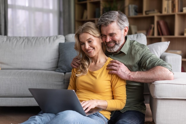 Online-Kommunikation Glückliche Ehepartner mittleren Alters mit Laptop-Computer zu Hause