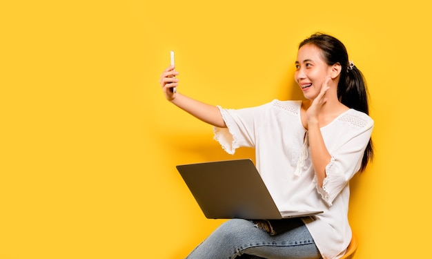 Online-Kommunikation von asiatischen Frauen Portrait des glücklichen asiatischen Geschäftsfrau, die Handy lokalisiert auf gelbem Hintergrund verwendet. Online-Kommunikationskonzept