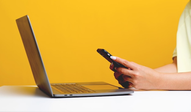 Online-Kommunikationsfrau, die Laptop- und Handy-Websurfen und Online-Weltarbeit zu Hause mit gelbem Hintergrund-Kommunikationskonzept verwendet