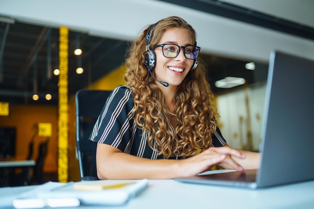 Online-Meeting Junge Frau mit Kopfhörern und Laptop, die sich ein Webinar ansieht oder einen Video-Chat macht