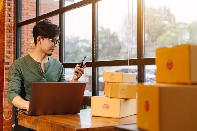 Online-Shopping asiatische junge starten kleine Unternehmen in einem Karton bei der Arbeit. Der Verkäufer bereitet die Lieferbox für den Kunden, den Online-Verkauf oder den E-Commerce vor.