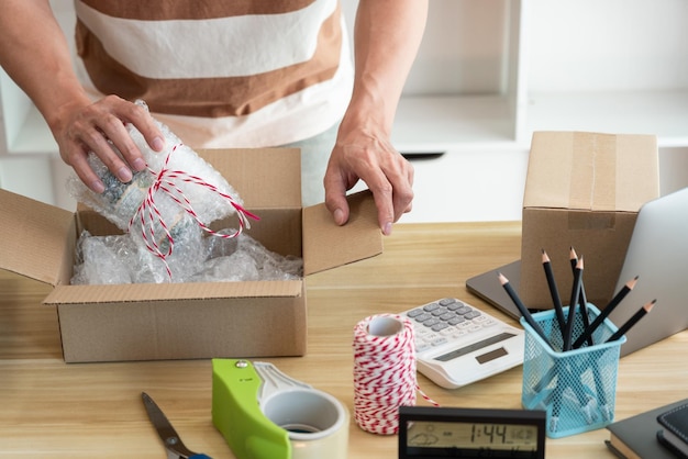 Foto online-shopping-konzept der ladenhändler verpackt sein produkt und legt es in die verpackung