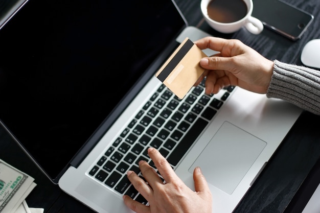 Online-Shopping-Konzept. Frau, die in der Hand Goldkreditkarte und das on-line-Einkaufen hält