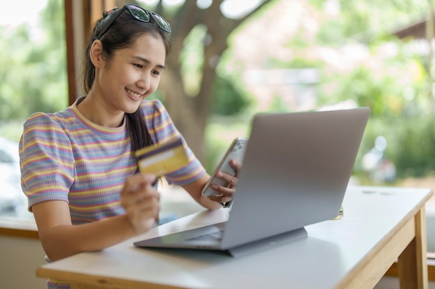 Online-Shopping und Internetzahlungen Porträt schöner asiatischer Frauen nutzen ihre Kreditkarten und Mobiltelefone, um online einzukaufen oder Besorgungen in der digitalen Welt zu erledigen