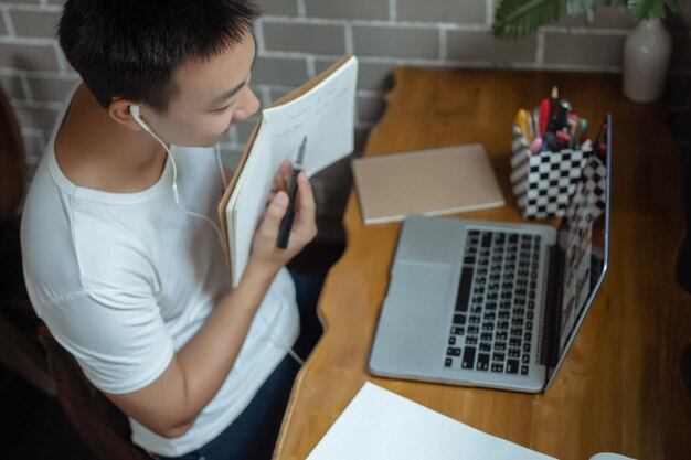 Online-Studienkonzept Der junge Mann präsentiert seinem Lehrer sein neues Konzept des Projekts, indem er seinen Plan in einem kleinen Buch über seinen Laptop zeigt.