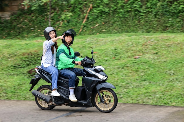 Foto online-taxi-motorradpassagier weist mit einem lächeln auf einen ort hin