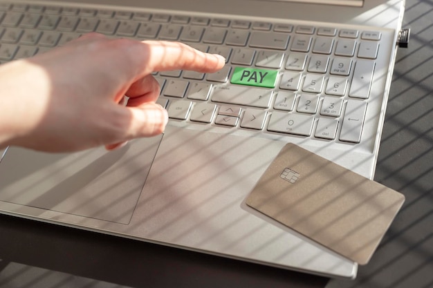 Online-Zahlungskonzept Handfinger, der die grüne sichere PAY-Taste auf der Laptoptastatur drückt