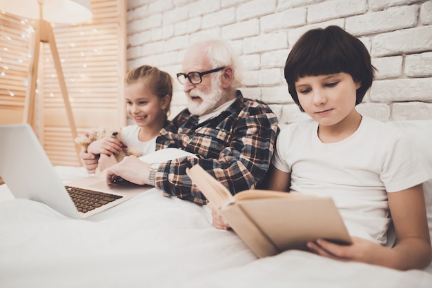 Opa und Kinder lesen und schauen Filme im Bett