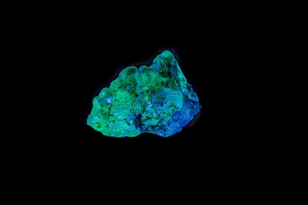 Opala de pedra mineral macro sob luz ultravioleta em um fundo preto