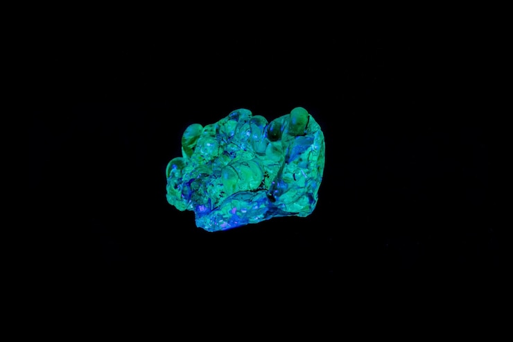 Foto opala de pedra mineral macro sob luz ultravioleta em um fundo preto