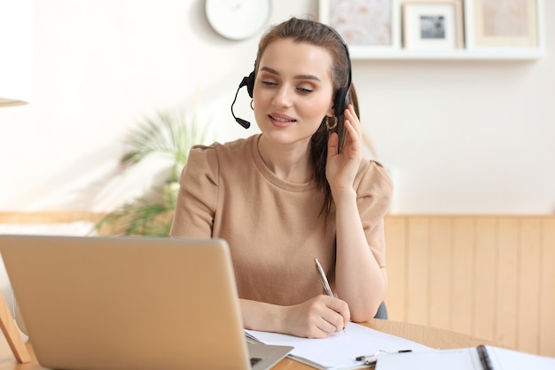 Operador autónomo hablando con auriculares y consultando a clientes desde casa.