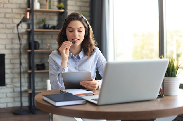 Operador autónomo hablando con auriculares y consultando a clientes desde casa.