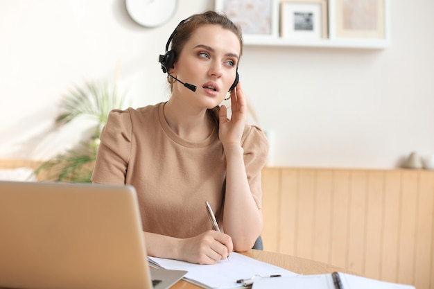 Operador autónomo hablando con auriculares y consultando a clientes desde casa.