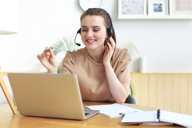 Operador autónomo hablando con auriculares y consultando a clientes desde casa.