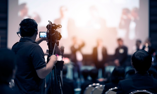 Operador de cámara de video trabajando con su equipo en un evento de interior