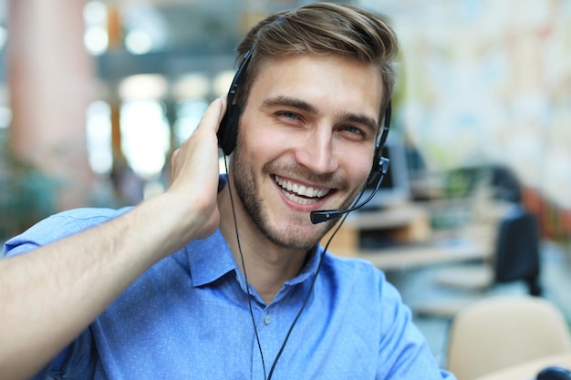 Operador de centro de llamadas masculino joven hermoso amistoso sonriente.