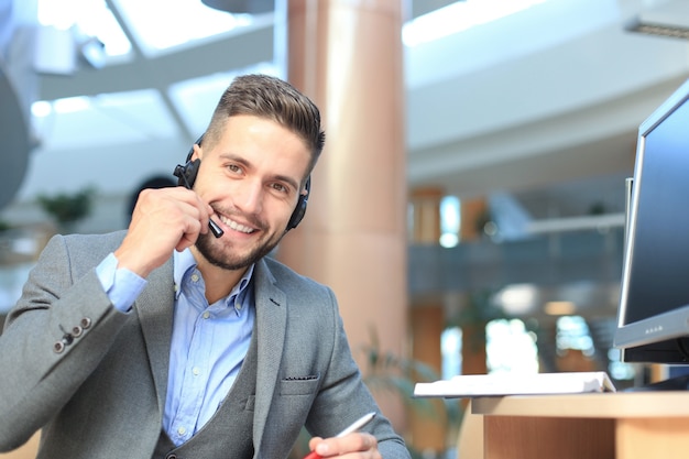 Operador de centro de llamadas masculino joven hermoso amistoso sonriente.