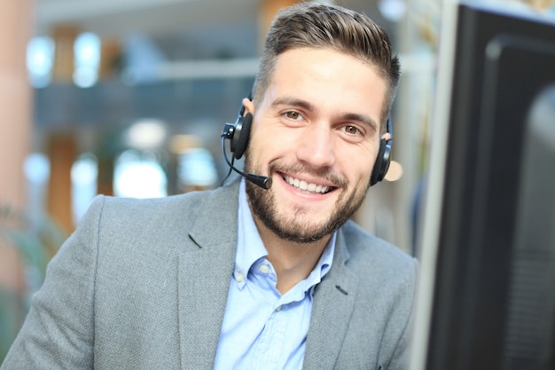 Operador de centro de llamadas masculino joven hermoso amistoso sonriente.