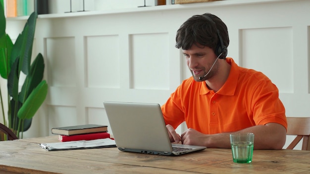 Operador de centro de llamadas masculino sonriente haciendo su trabajo con un auricular.