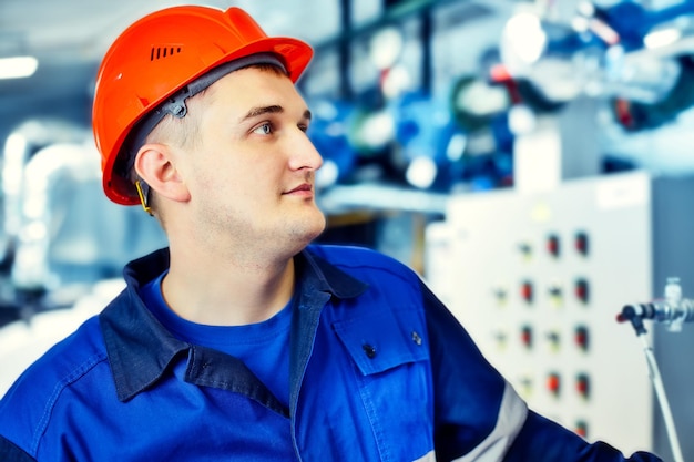 Operador da casa de caldeira a gás verifica a pressão no equipamento Retrato de engenheiro no capacete no trabalho Homem de trabalho de fluxo de trabalho de cena autêntica na sala da caldeira Fundo desfocado Gaseificação e energia