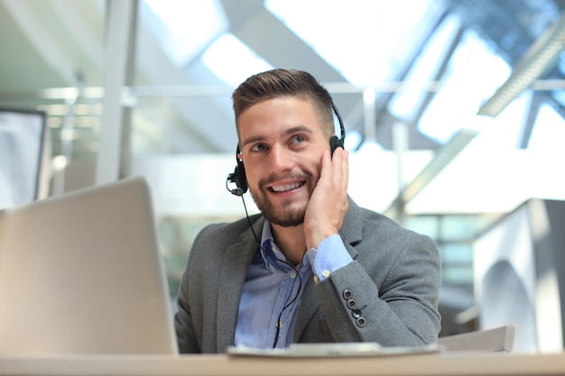 Operador de call center masculino jovem bonito amigável a sorrir.