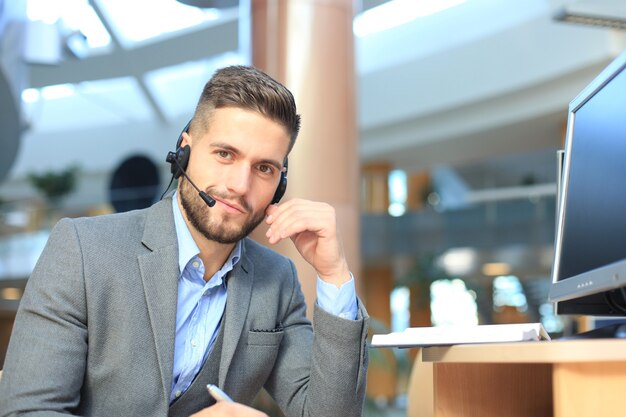 Operador de call center masculino jovem bonito amigável a sorrir.