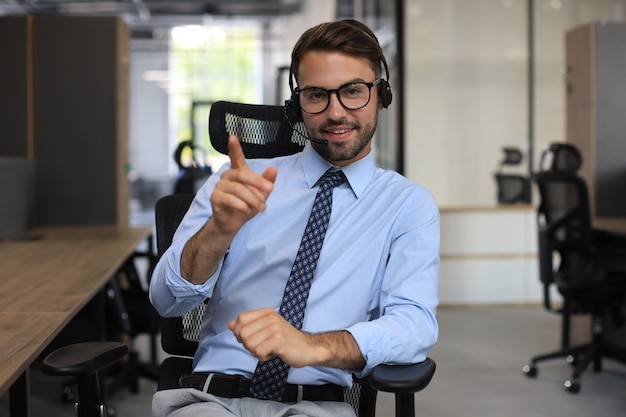 Operador de call center masculino jovem bonito amigável a sorrir.