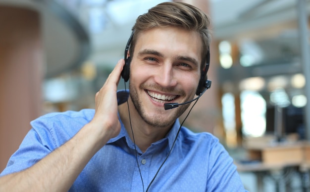 Operador de call center masculino jovem bonito amigável a sorrir.