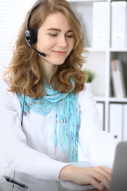 Operador de chamada ou mulher de negócios no fone de ouvido trabalhando com laptop no escritório