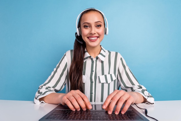 Operador de linha de apoio feminino amigável, sentado na mesa, usa clientes de chamada de vídeo lnetbook isolados em fundo de cor azul