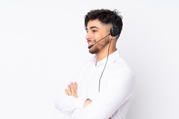 Operador de telemarketing homem árabe trabalhando com um fone de ouvido na parede branca