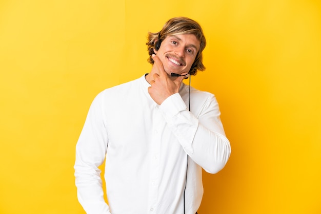 Operador de telemarketing trabalhando com um fone de ouvido isolado na parede amarela feliz e sorridente