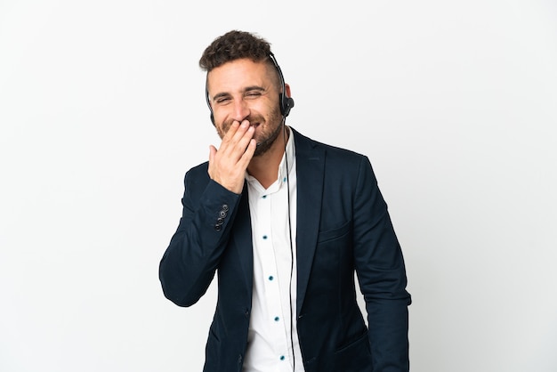 Operador de telemarketing trabalhando com um fone de ouvido isolado no fundo branco, feliz e sorridente, cobrindo a boca com a mão