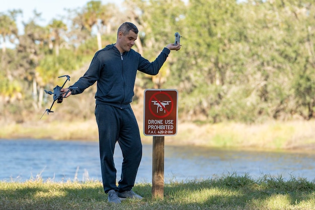 El operador está decepcionado porque no puede volar su cuadricóptero en un parque nacional sin área de drones El hombre no puede usar su UAV cerca de la señal de aviso de restricción