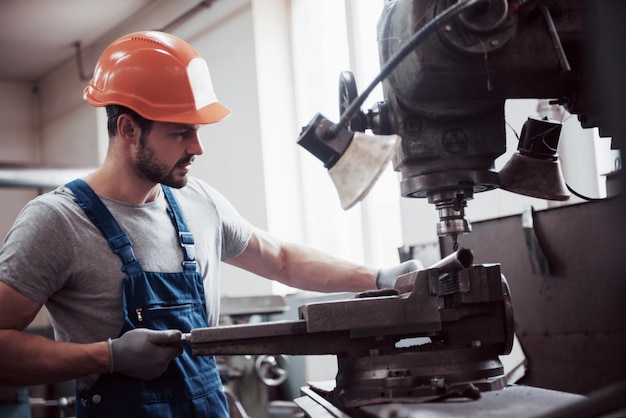 Operador experimentado en un concepto de industria metalúrgica de sombrero duro ingeniero profesional metalúrgico que opera un centro de máquinas de fresado CNC en un taller de fabricación